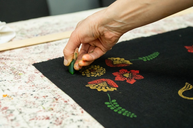 Mâini care brodează un motiv floral